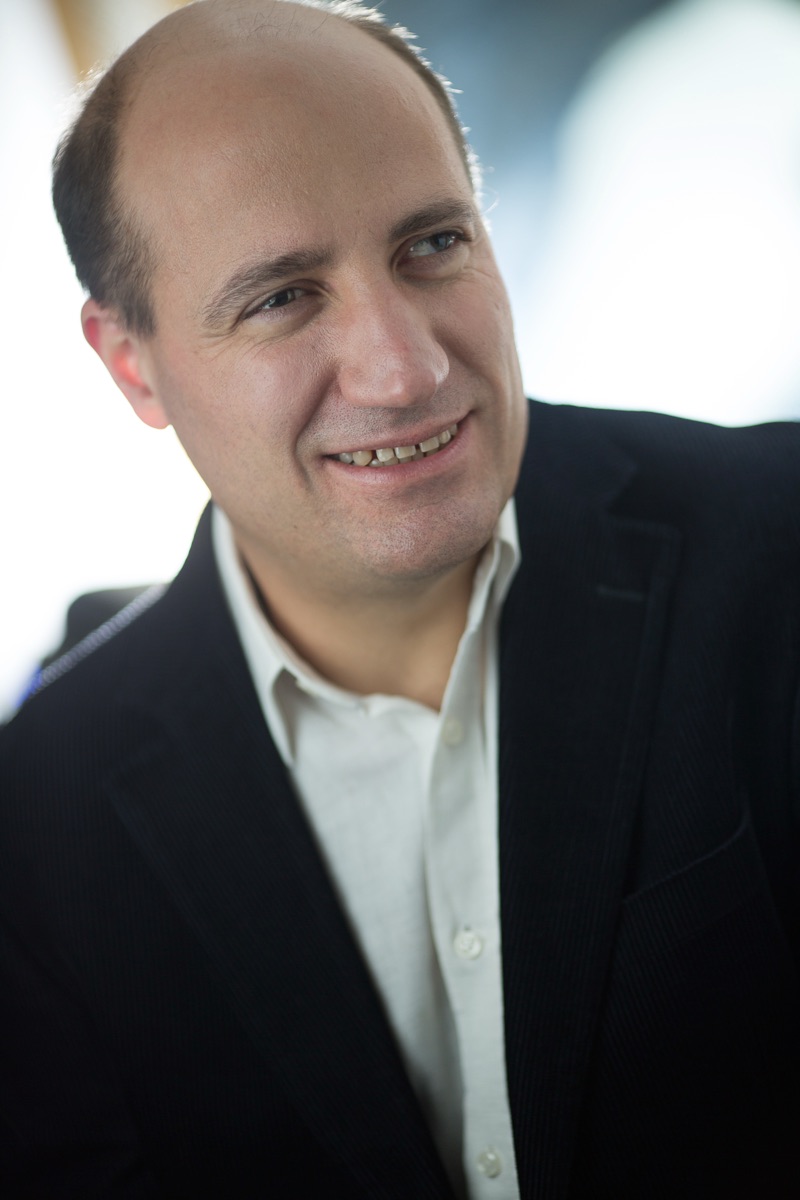 Jérôme Adam, souriant, en veste sombre et chemise blanche.