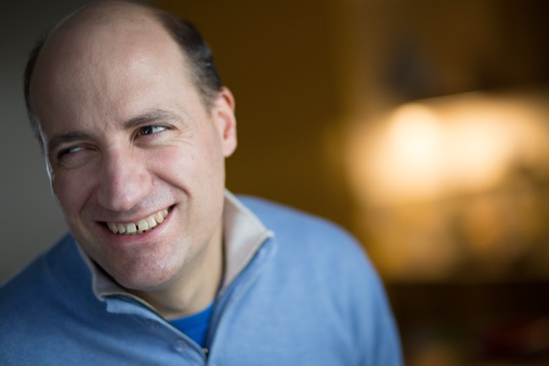 Jérôme Adam, en pull bleu ciel, avec un large sourire.